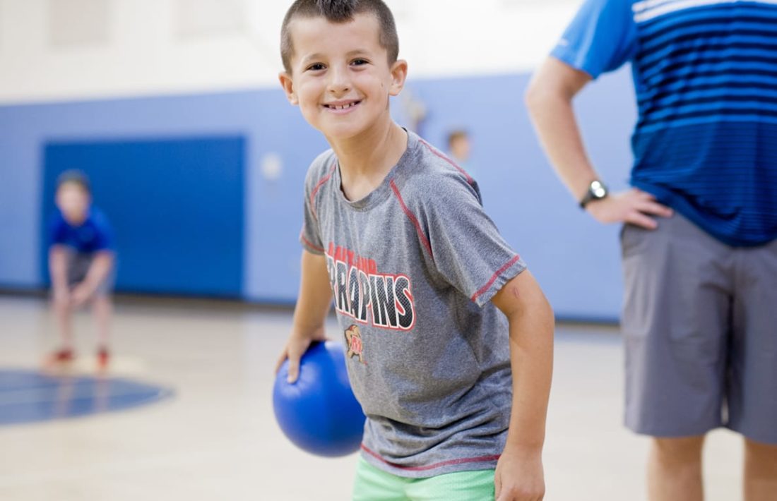 Boy holding a dodgeball in the gym