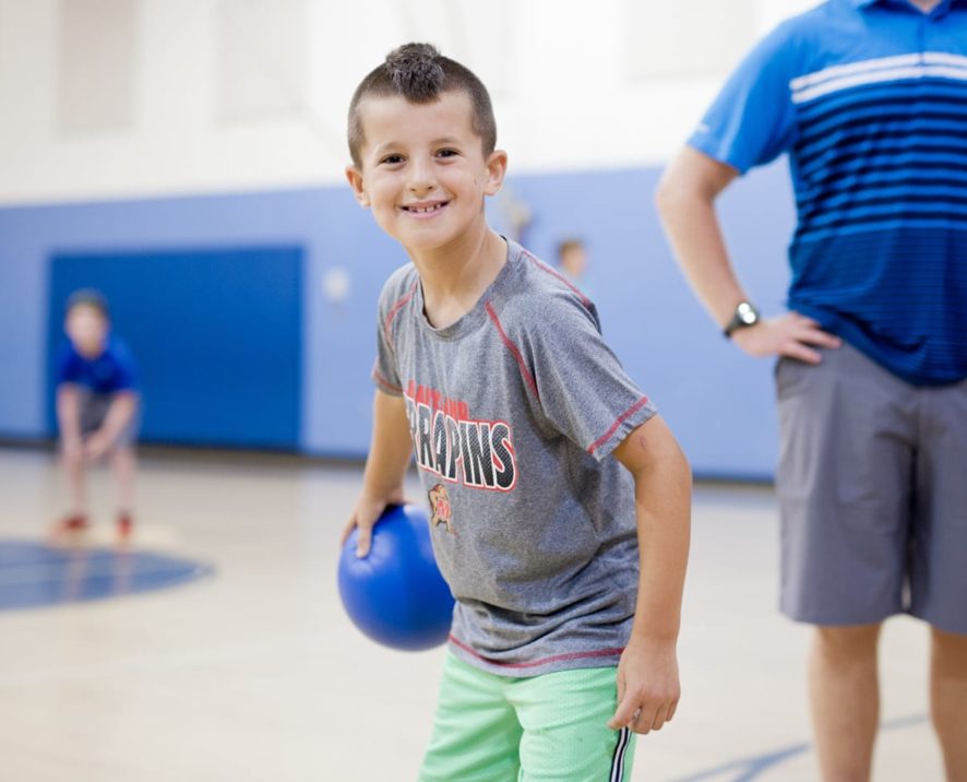 Boy holding a dodgeball in the gym